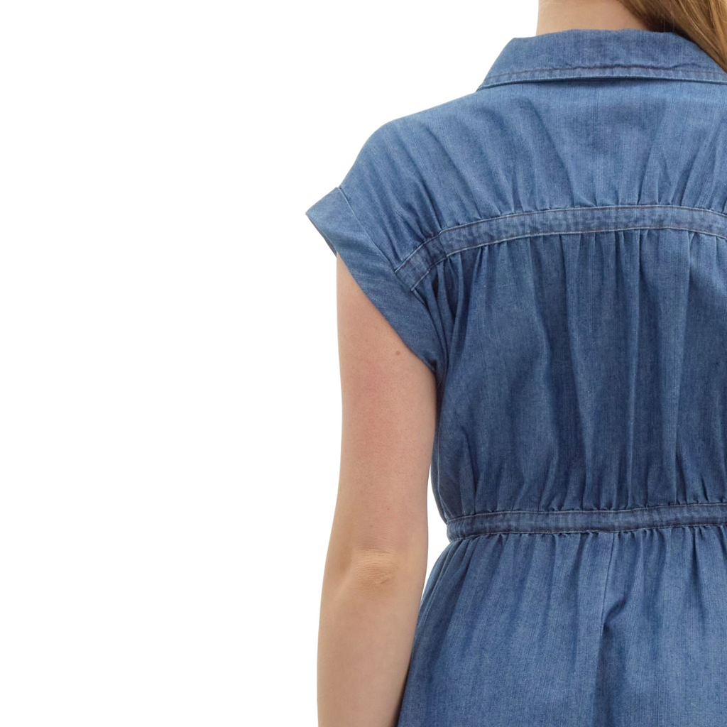 A woman is wearing a knee-length, short-sleeved denim dress with a collar, a full-length zipper down the front, and a drawstring waist.