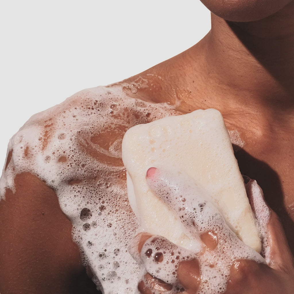 Model rubbing a sudsy Beekman 1802 Honey & Orange Blossom 9 oz Goat Milk Soap onto their shoulder. #1
